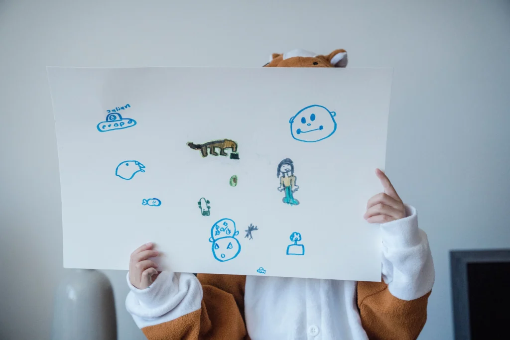 Copil care își arată desenul